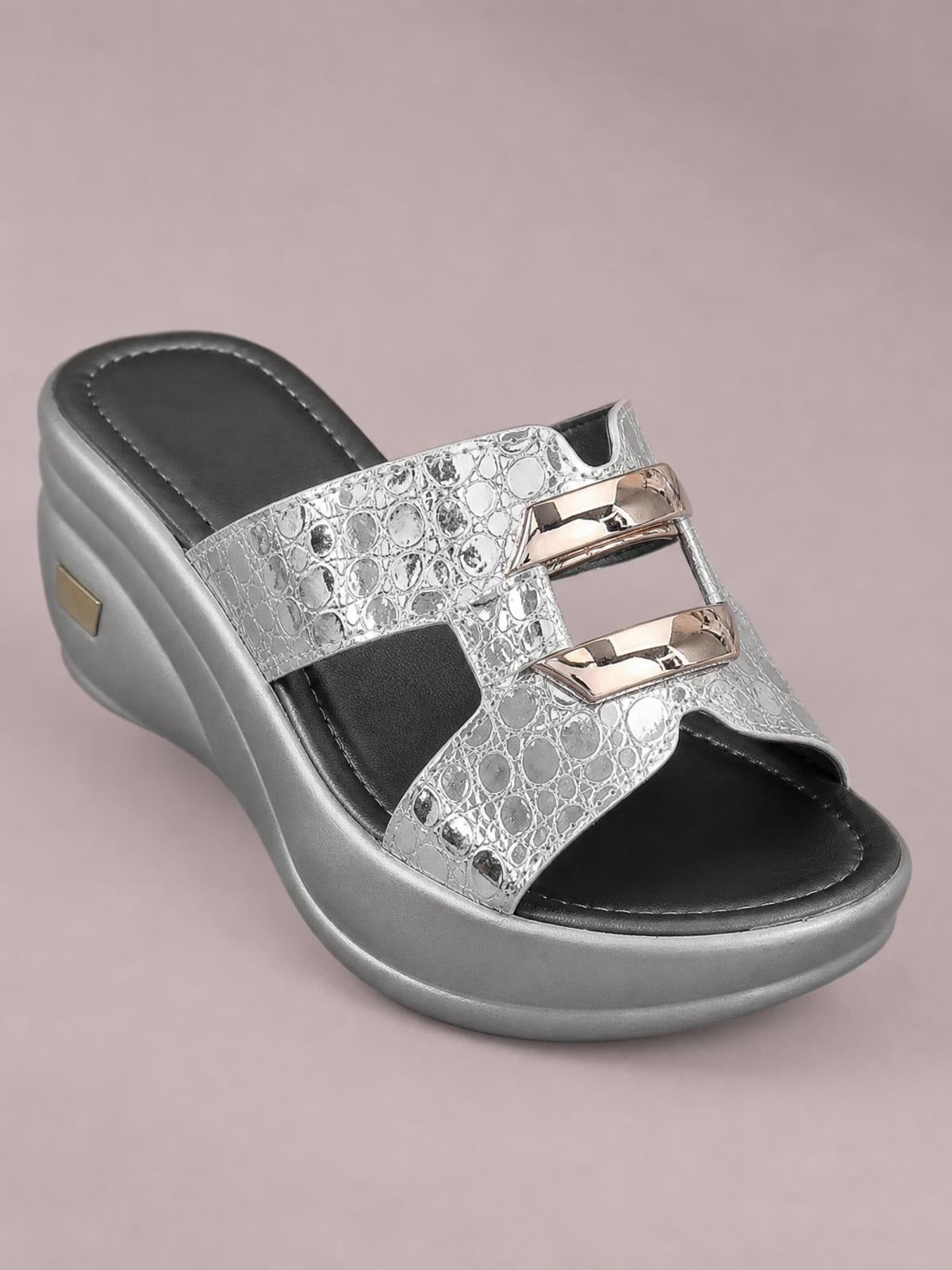 Silver open-toe platform wedge sandal with a textured patterned upper, layered metallic accents, black footbed, and a mid-height sculpted wedge sole.