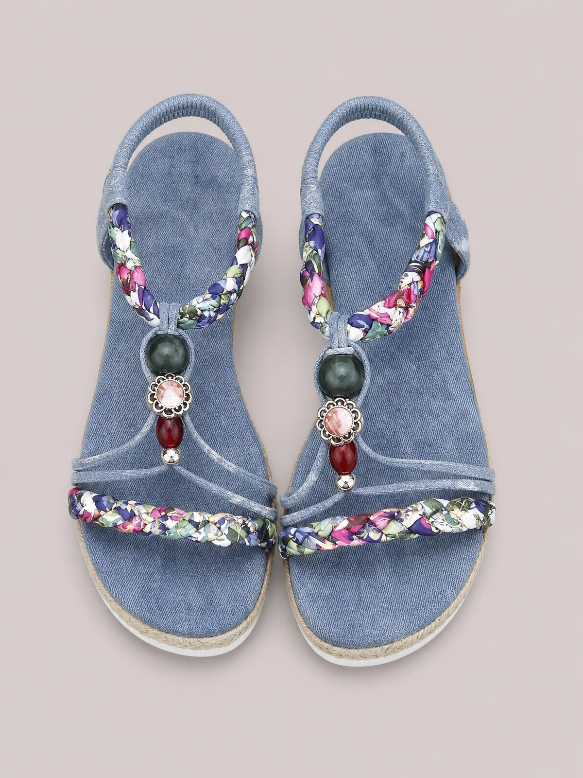 Blue open-toe platform wedge sandals feature braided floral straps, T-strap beaded embellishments, and straw-trimmed soles for a colorful bohemian look.