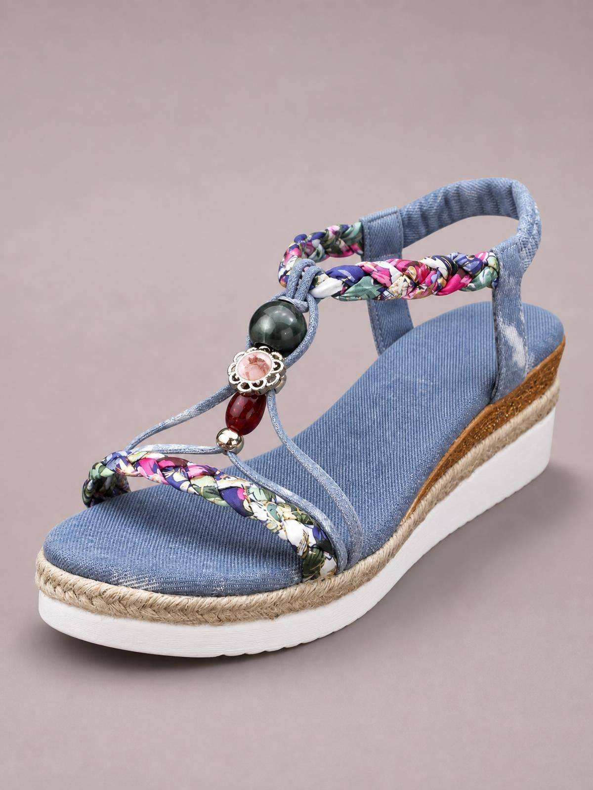 Blue open-toe platform wedge sandal with floral braided straps, beaded embellishment, ankle strap, espadrille-style trim, and a thick white sole.