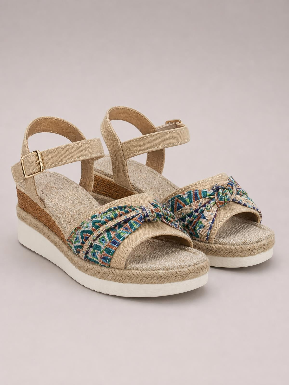 Beige open toe platform wedge sandals feature multicolor patterned bow straps, adjustable ankle buckles, textured insoles, and mid-height espadrille-style wedges.