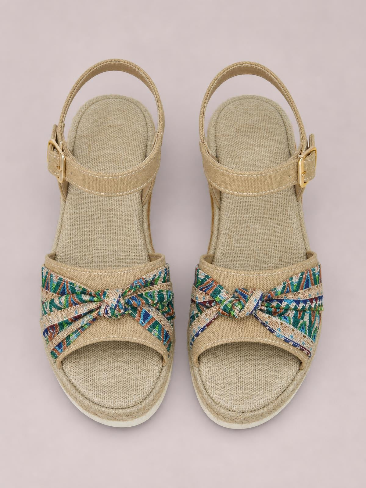 Tan open-toe platform wedge sandals feature ankle buckle straps, colorful patterned crossover bands with knotted bows, and a textured mid-height wedge sole.