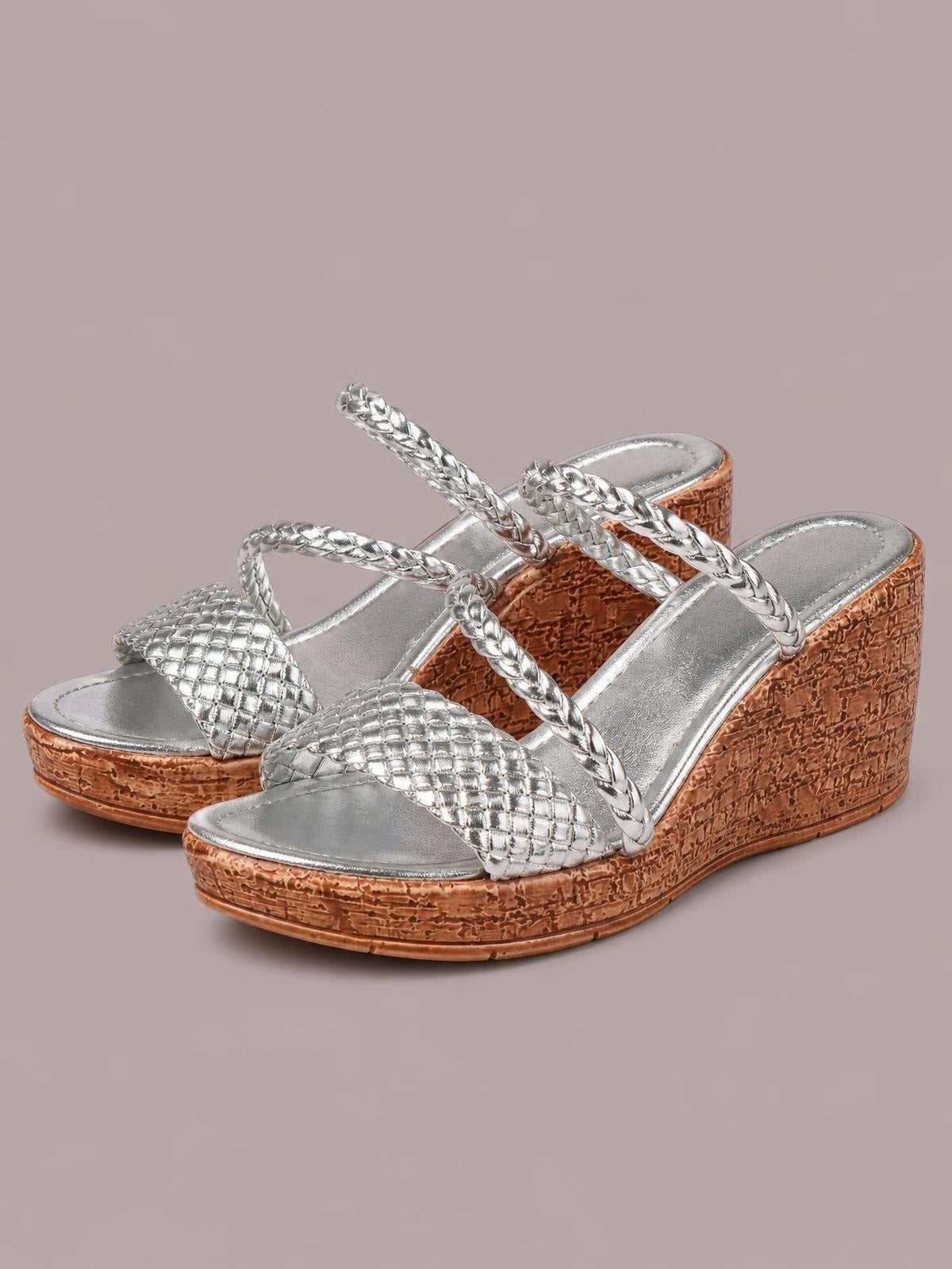 Silver open toe wedge sandals feature braided straps, quilted metallic toe bands, and textured brown mid-height wedge heels with a platform sole.