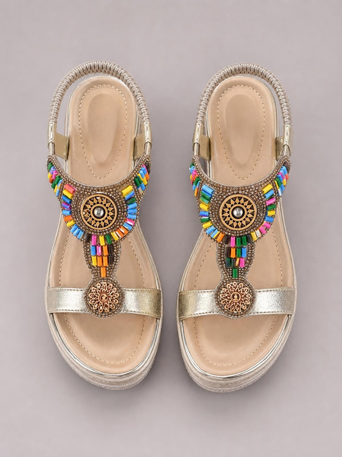 Metallic gold open toe wedge sandals feature wide toe straps, colorful beaded accents, ornate circular medallions, and cushioned insoles.