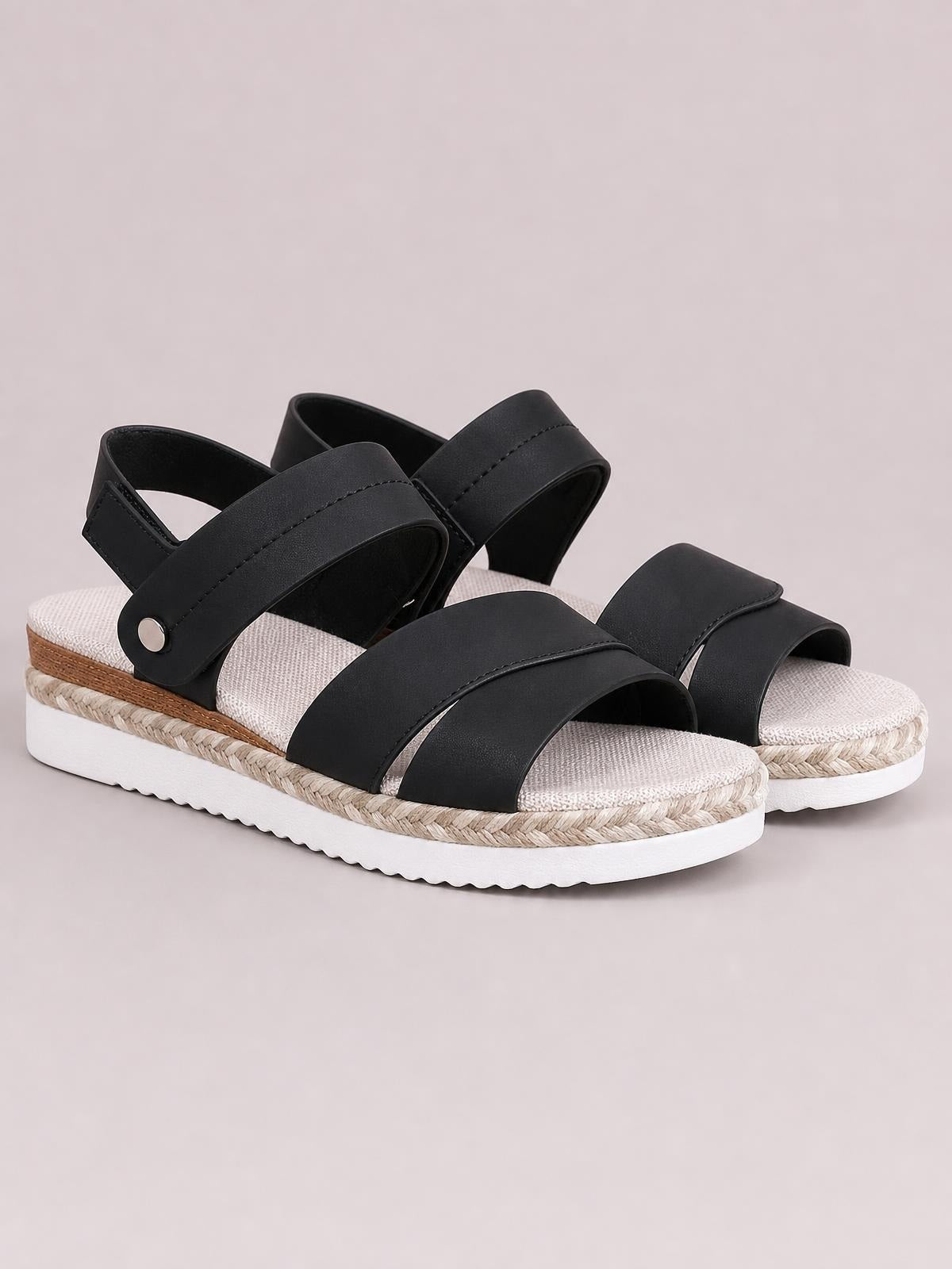 Black open-toe wedge sandals with wide stitched straps, ankle closures, woven espadrille trim, and a white rubber platform sole.