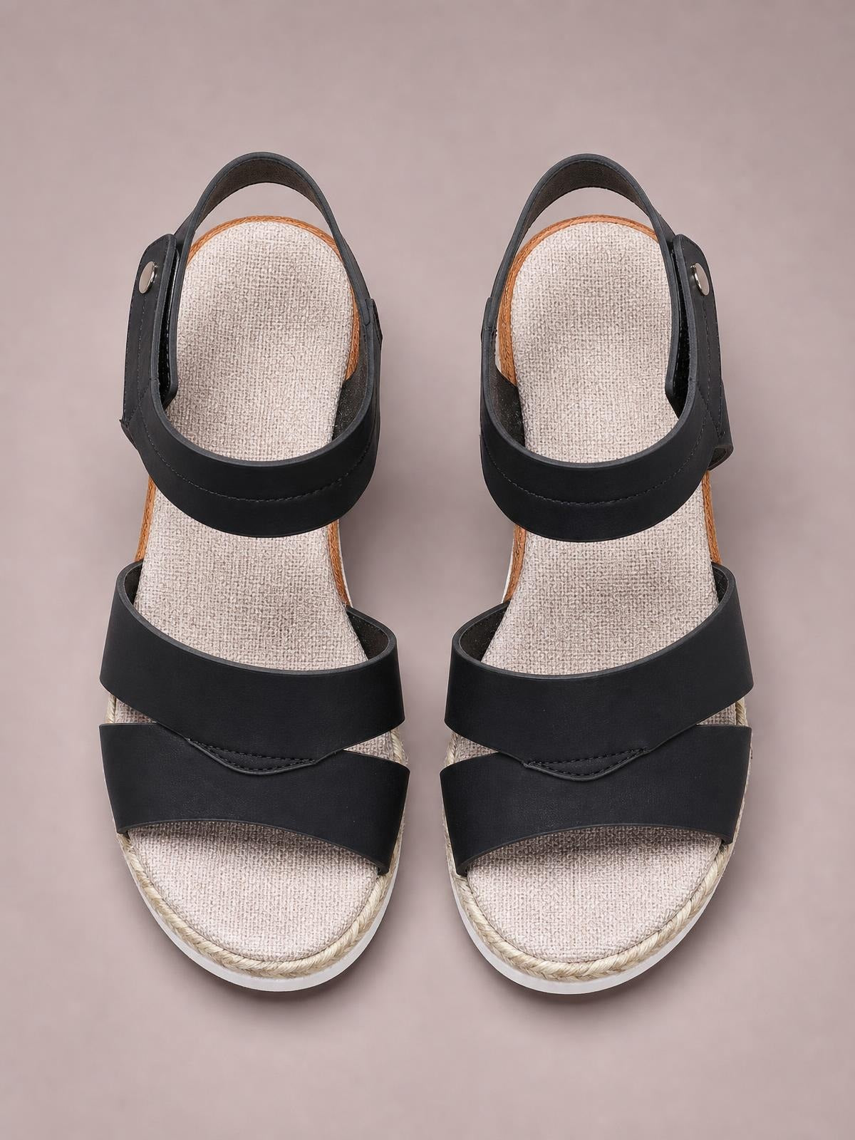Black open toe wedge sandals with wide crossover straps, ankle buckles, textured insoles, and rope-trimmed mid-height wedge soles.
