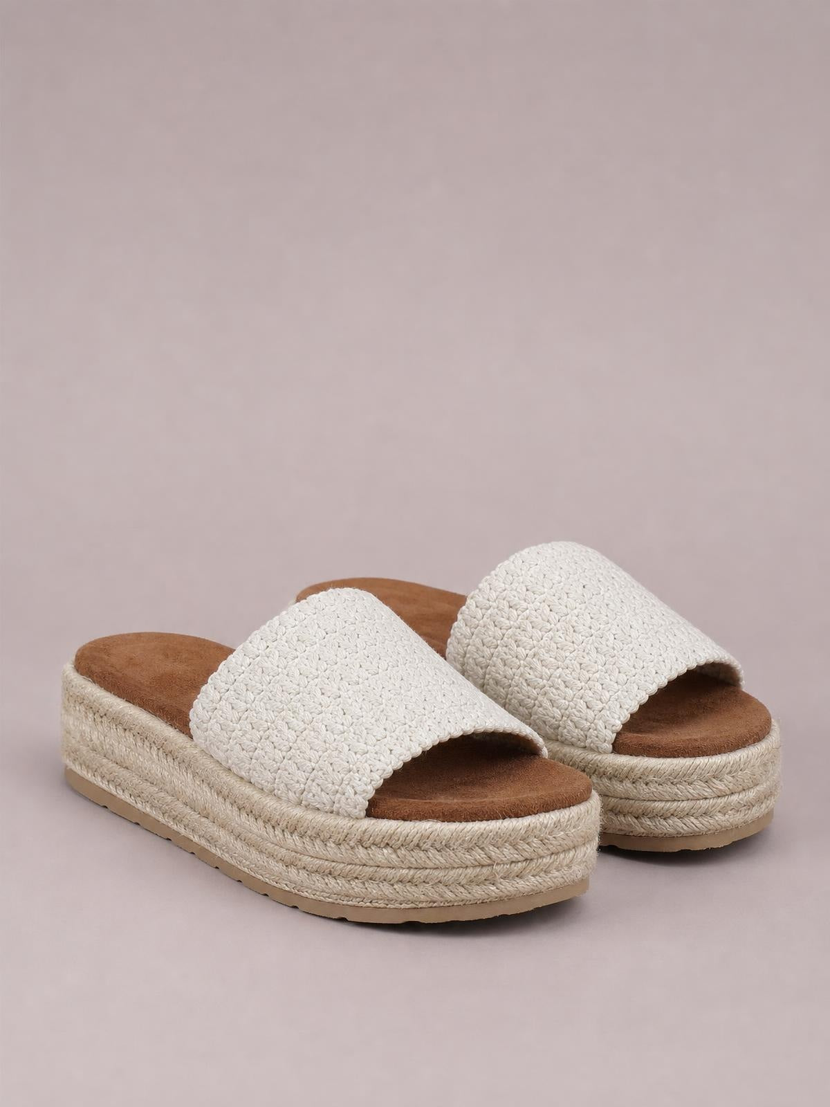 Cream open-toe woven platform sandals feature wide textured straps, cushioned brown footbeds, and layered braided espadrille-style soles.