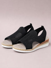 Black open-toe woven wedge sandals with mid-height heels, textured espadrille-style trim, cushioned footbeds, and white rubber platform soles.