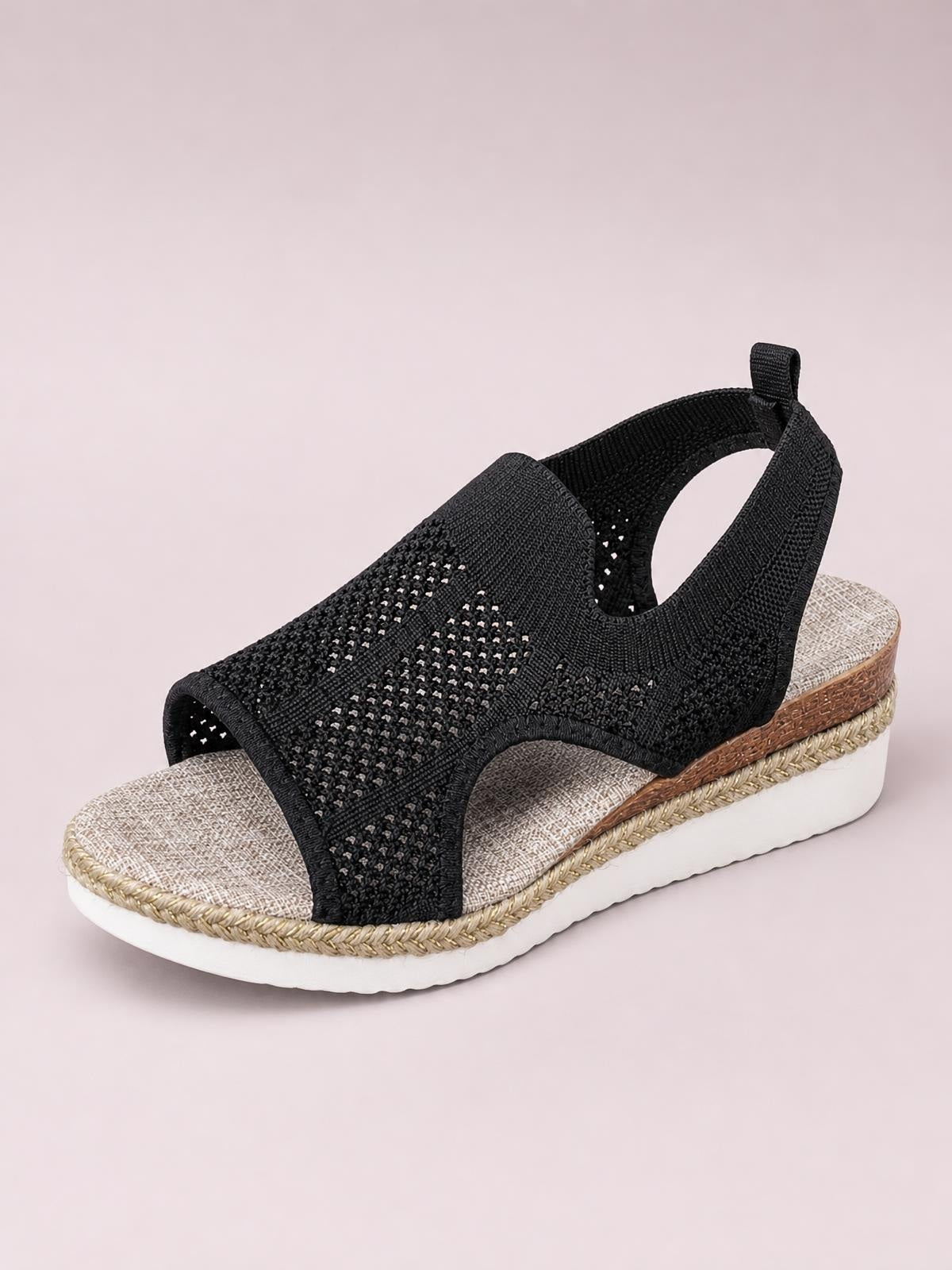 Black open toe woven wedge sandal with a wide textured upper, ankle strap, cushioned footbed, and mid-height platform sole with braided trim.