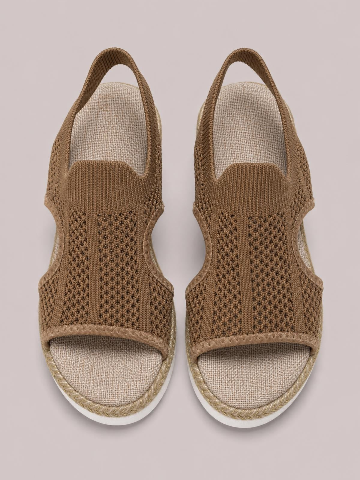 Pair of brown woven open-toe wedge sandals with broad textured straps, cushioned footbeds, braided trim, and white rubber soles.