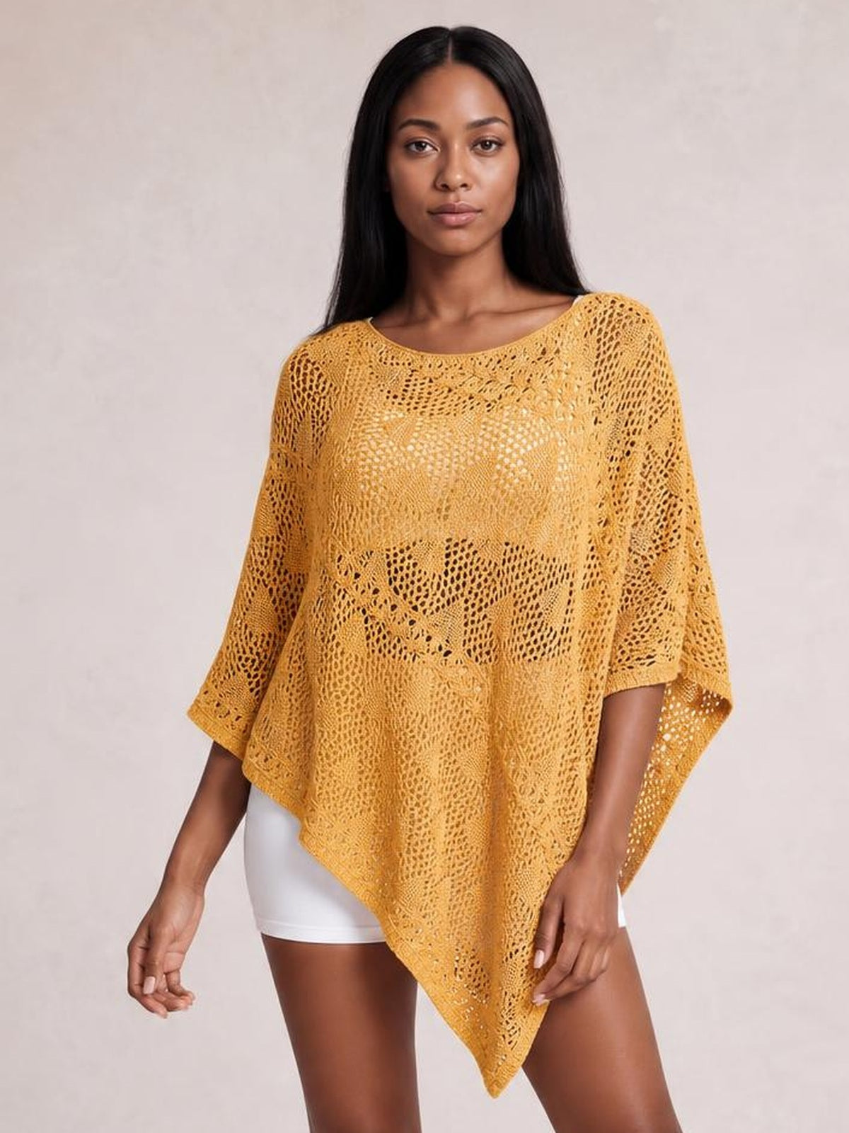Model stands facing forward in a mustard-yellow openwork shawl cover up with a boat neckline, wide sleeves, and a draped pointed-hem silhouette.