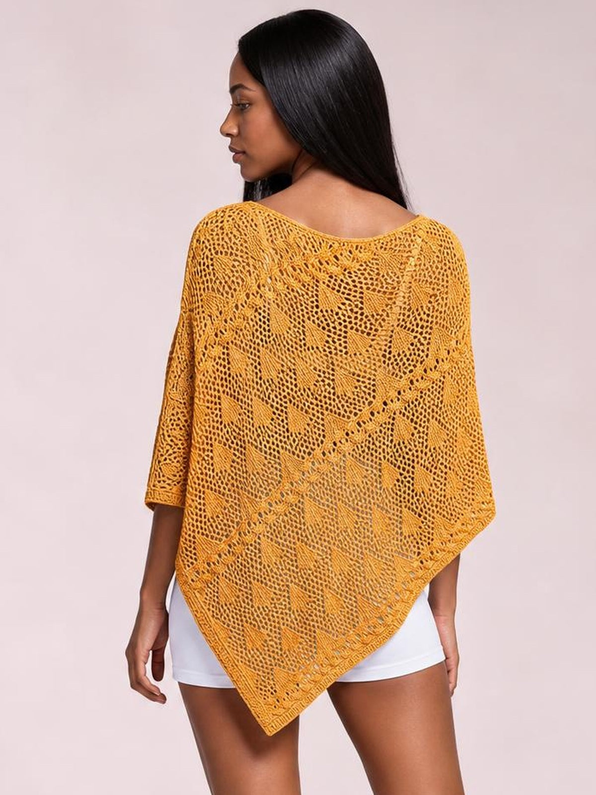 Model shown from the back wearing a mustard yellow openwork boat neck shawl cover up with a loose poncho silhouette and pointed hem.