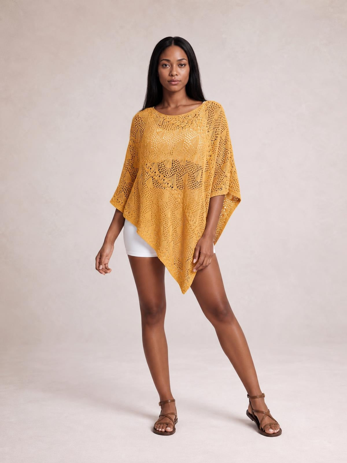 Model poses in a mustard-yellow openwork boat neck shawl cover up with a loose poncho silhouette, pointed hem, and wide three-quarter sleeves.