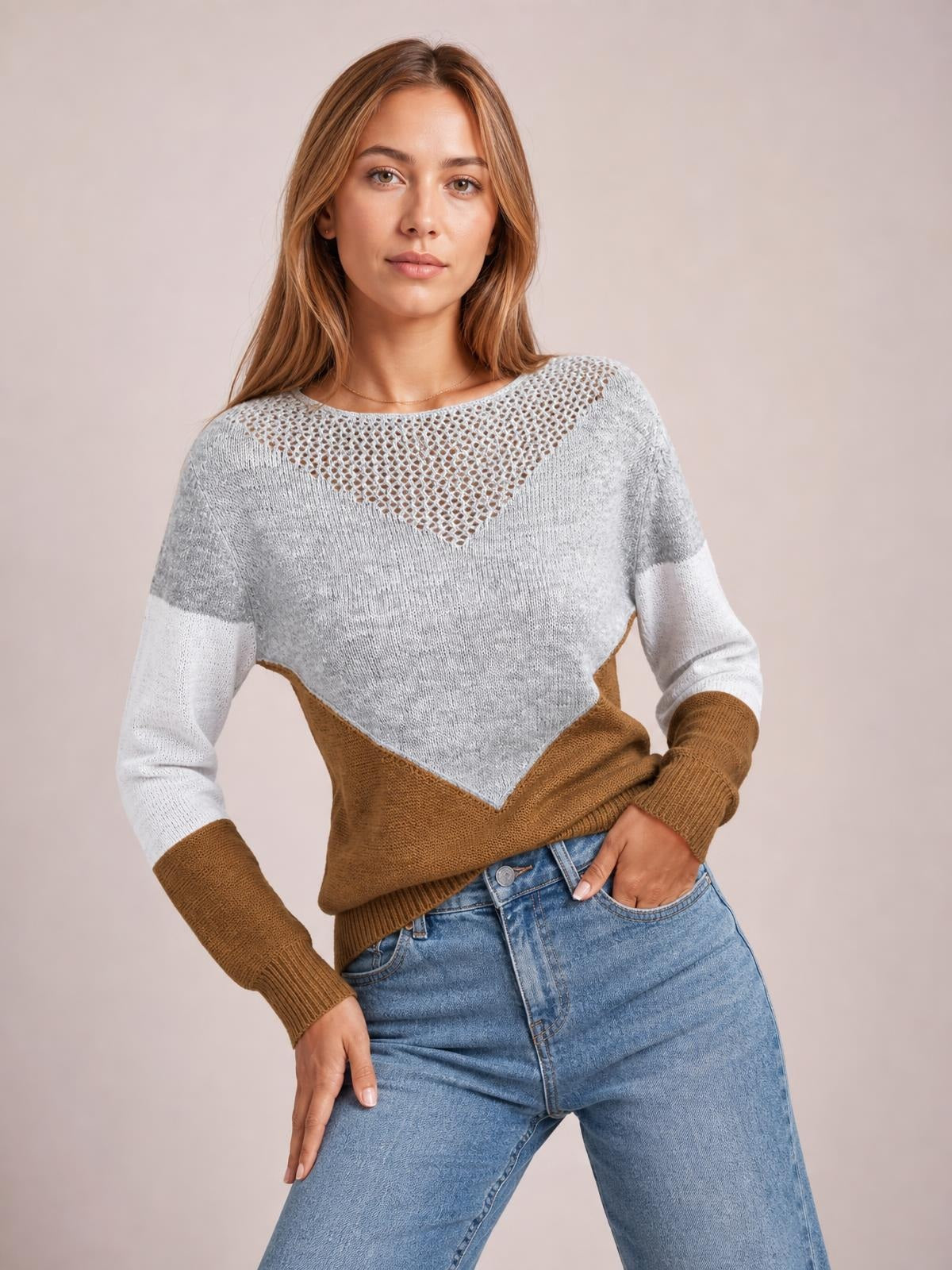 Model poses in a color-block long-sleeve sweater with a gray openwork neckline, white sleeves, brown lower section, and relaxed silhouette.