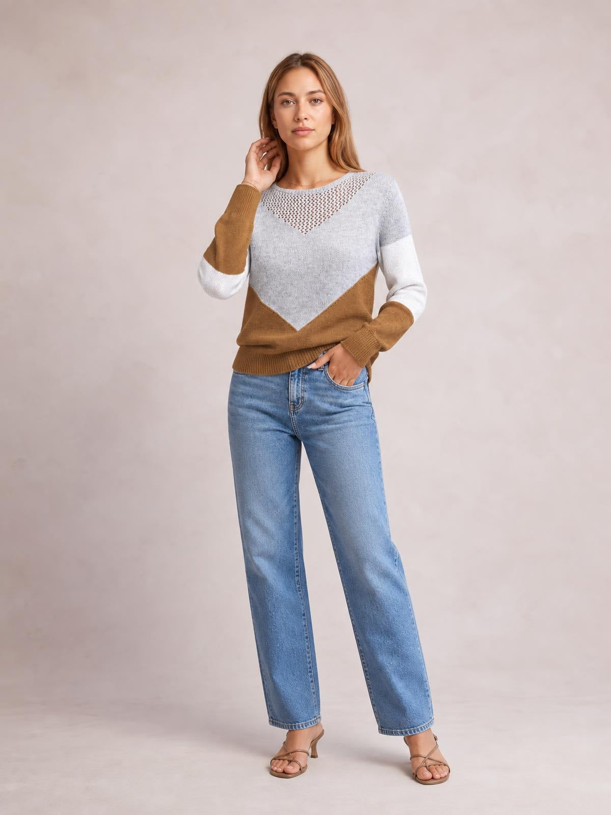 Model poses in a long-sleeve openwork color-block sweater with gray, white, and camel panels, a relaxed silhouette, and ribbed cuffs and hem.