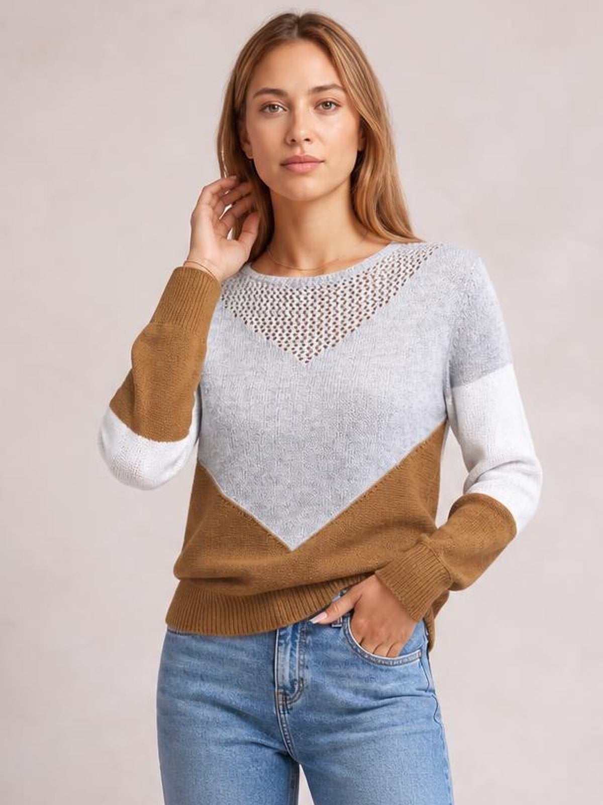 A model poses in a color-block long sleeve sweater with gray, camel, and white panels, an openwork yoke, relaxed silhouette, and ribbed cuffs and hem.