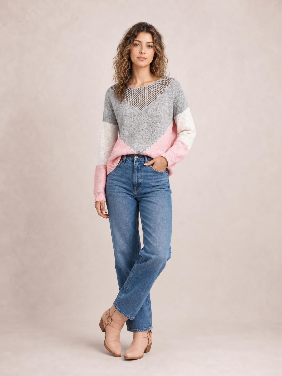 Model poses in a gray, pink, and white color block long sleeve sweater with an openwork neckline and relaxed silhouette.