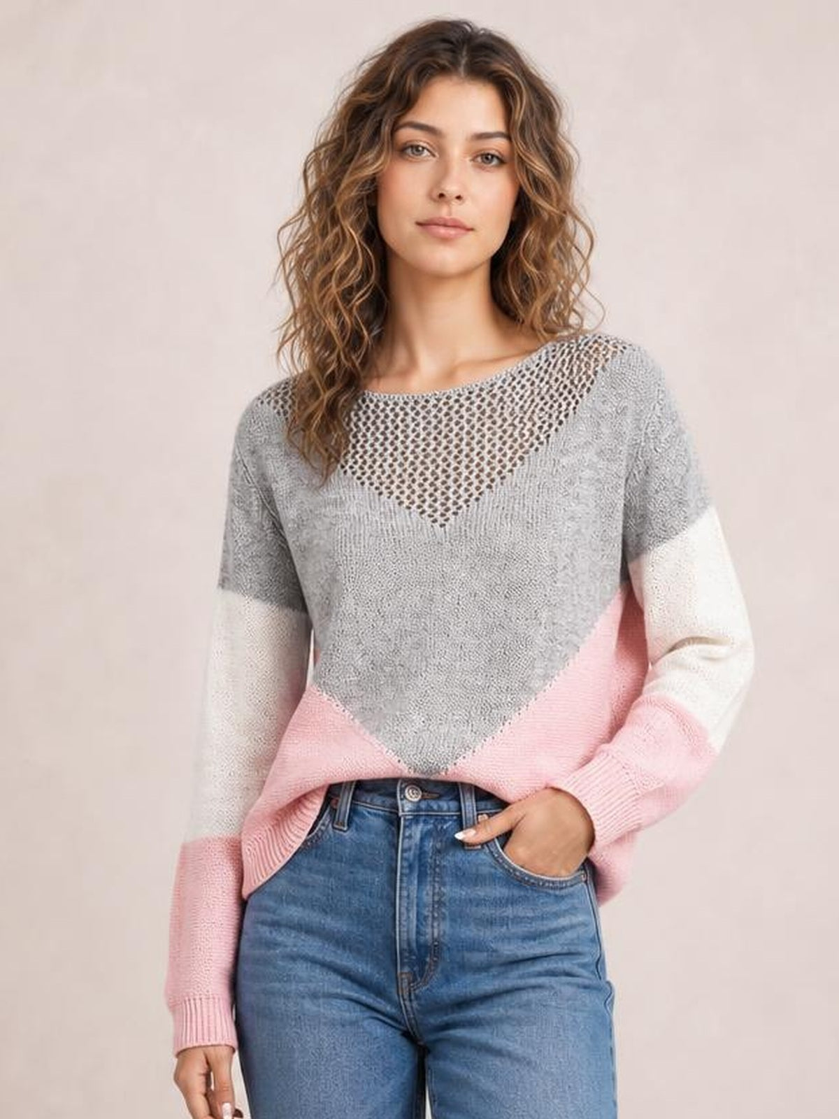 Model wears a relaxed color block long sleeve sweater with gray, white, and pink panels, an openwork neckline, and ribbed cuffs.