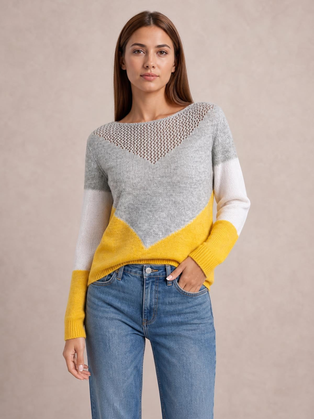 Model poses in a gray, yellow, and white color block long sleeve sweater with an openwork V-shaped yoke, ribbed cuffs, and a relaxed silhouette.