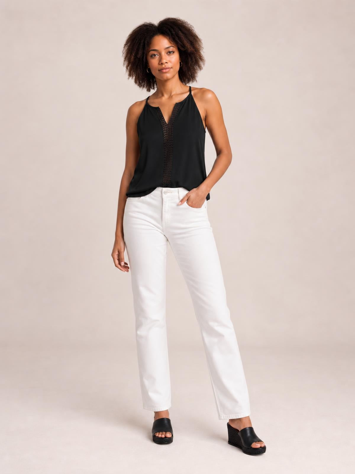 Model poses in a black semi-sheer openwork cami with thin straps, a notched neckline, straight relaxed silhouette, and decorative center panel.