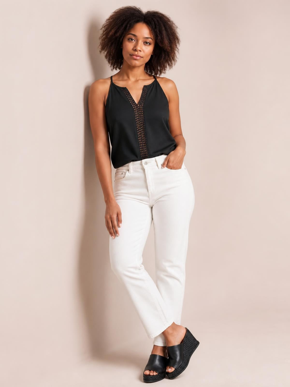 Model poses in a black openwork notched cami with a semi-sheer V-shaped panel, slim straps, and relaxed straight silhouette.