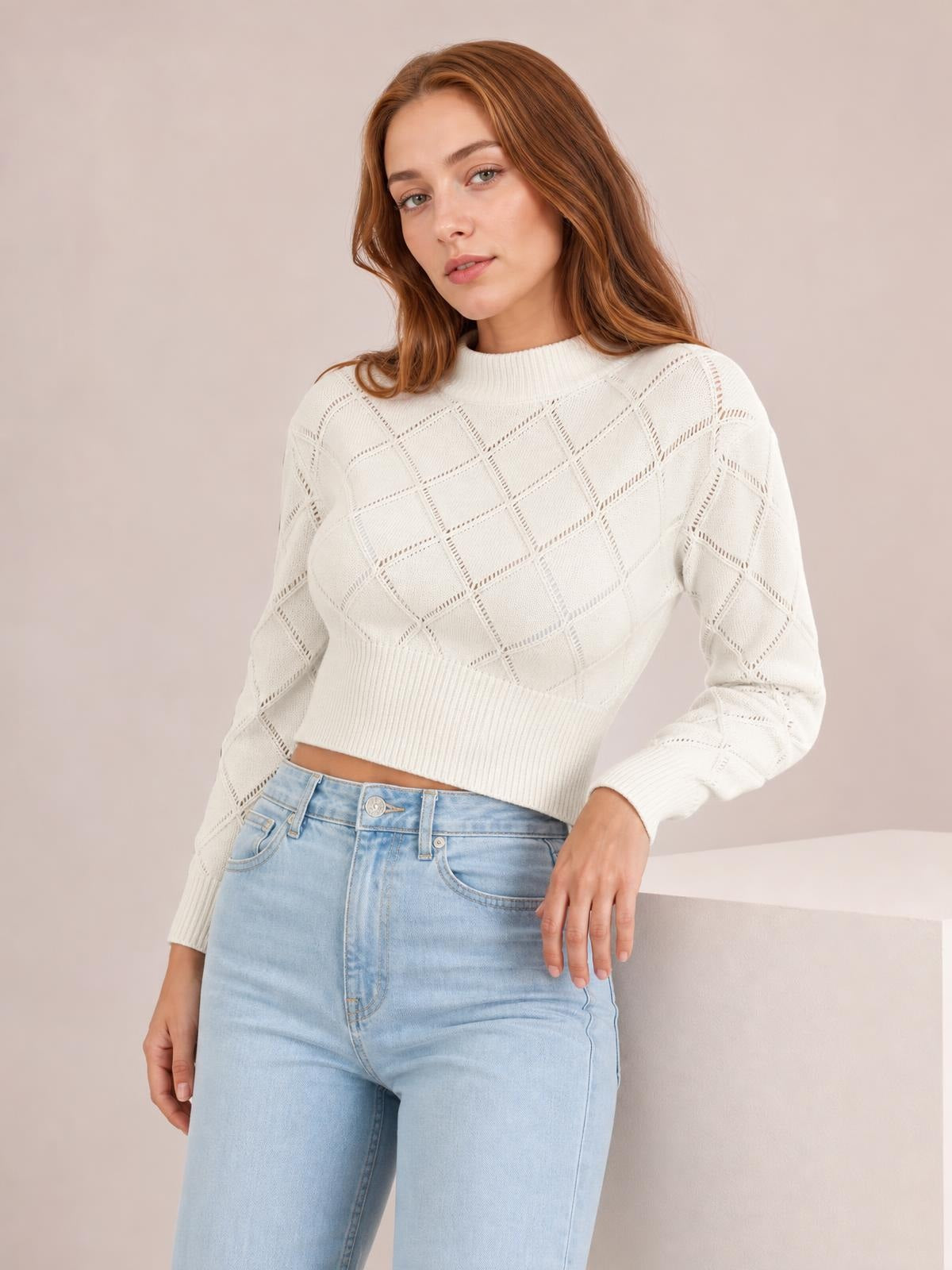 A model poses in an ivory openwork plaid cropped sweater with a round neck, long sleeves, ribbed cuffs and hem, and a relaxed fitted silhouette.