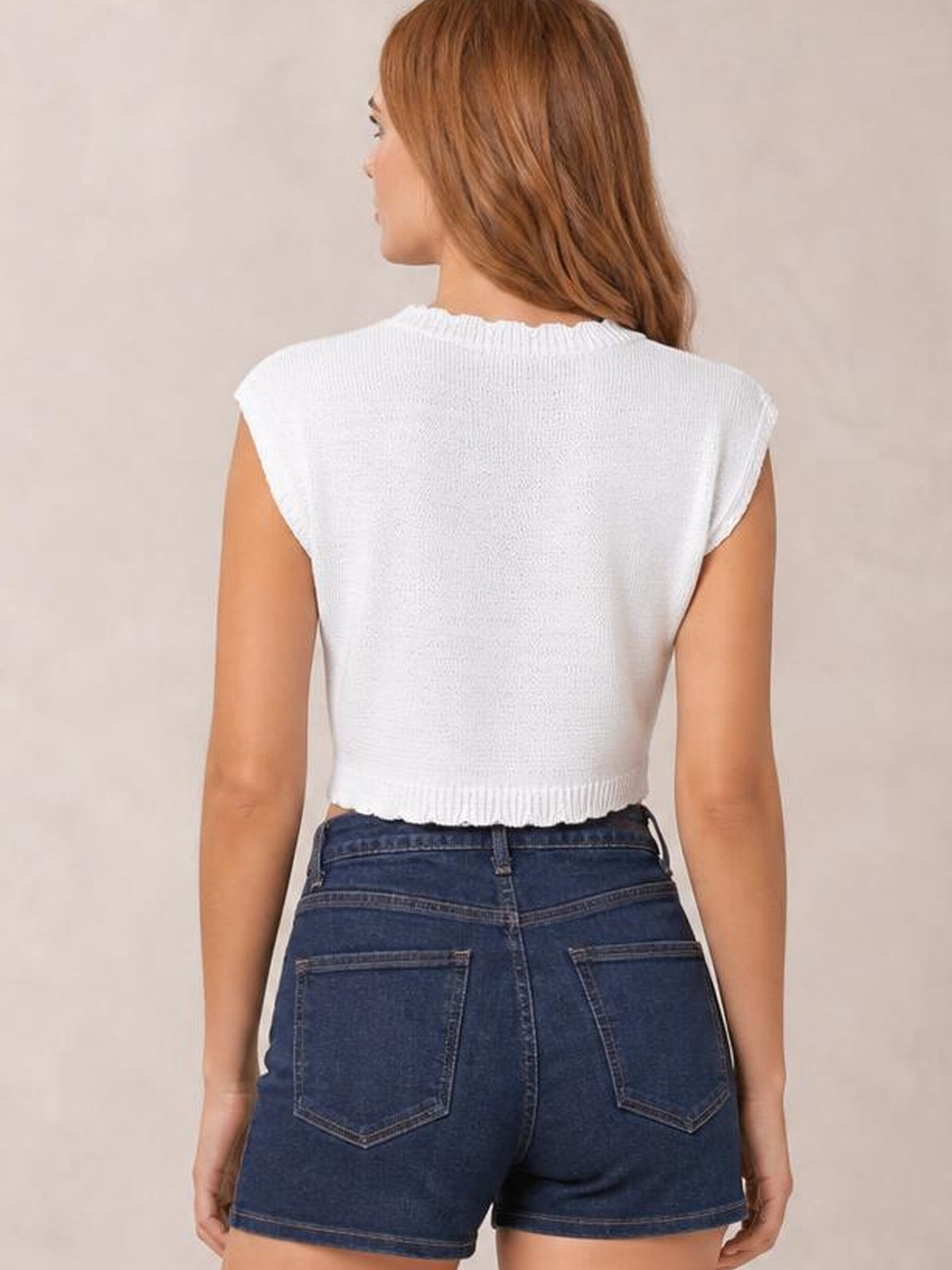 Model shown from the back wearing a white openwork round neck knit top with cap sleeves, a cropped silhouette, and ribbed neckline and hem.