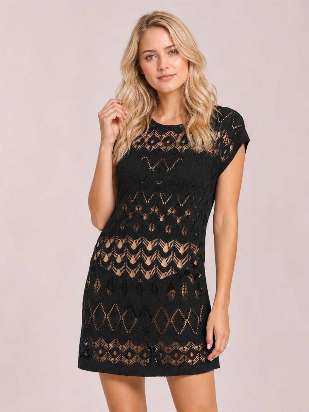 Model wearing a black openwork round neck cover-up with short sleeves, geometric cutout pattern, relaxed straight silhouette, and mini length.
