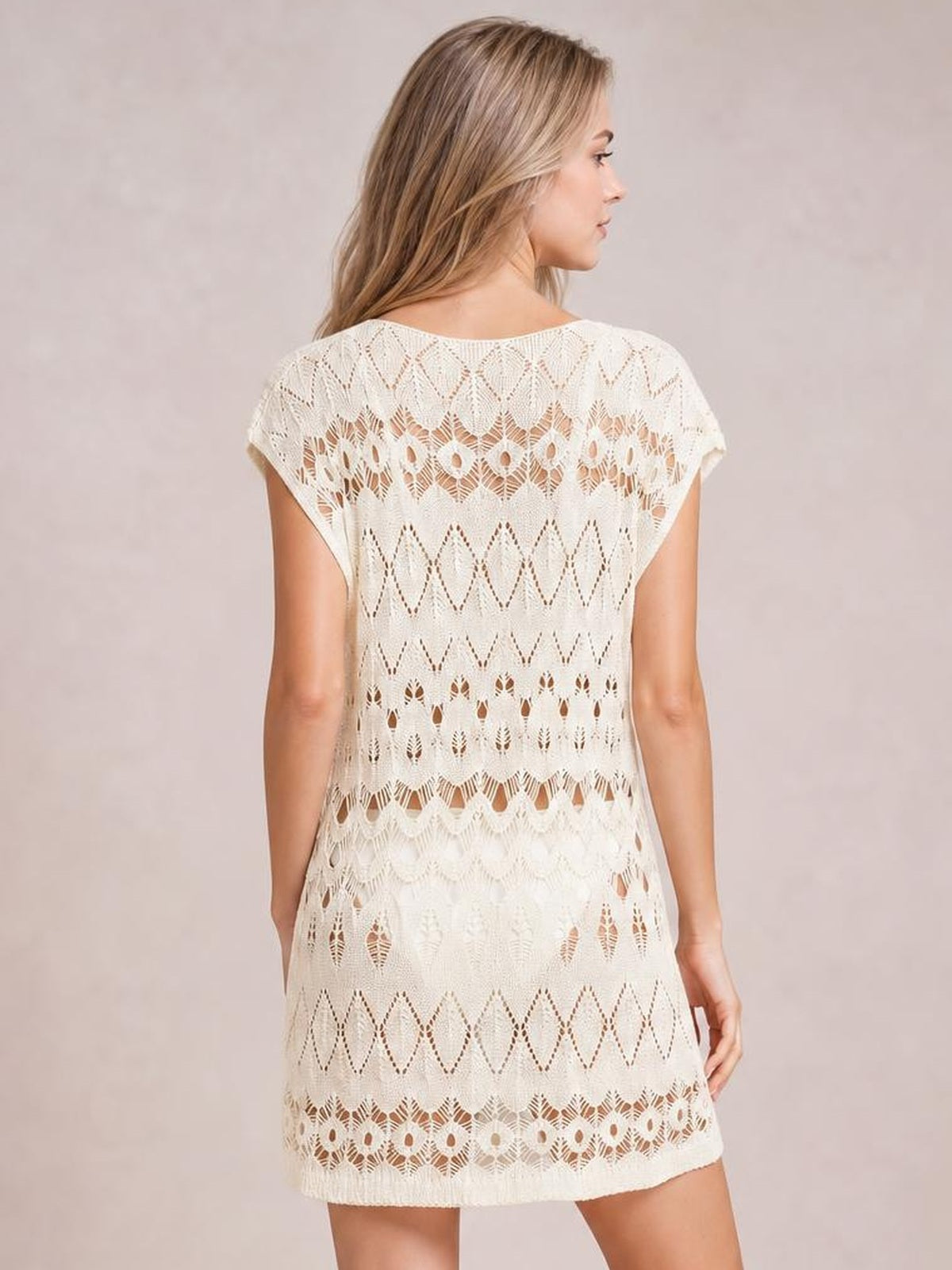 Model shown from behind in a white openwork round-neck cover-up with short sleeves, a relaxed straight silhouette, and patterned crochet-style construction.