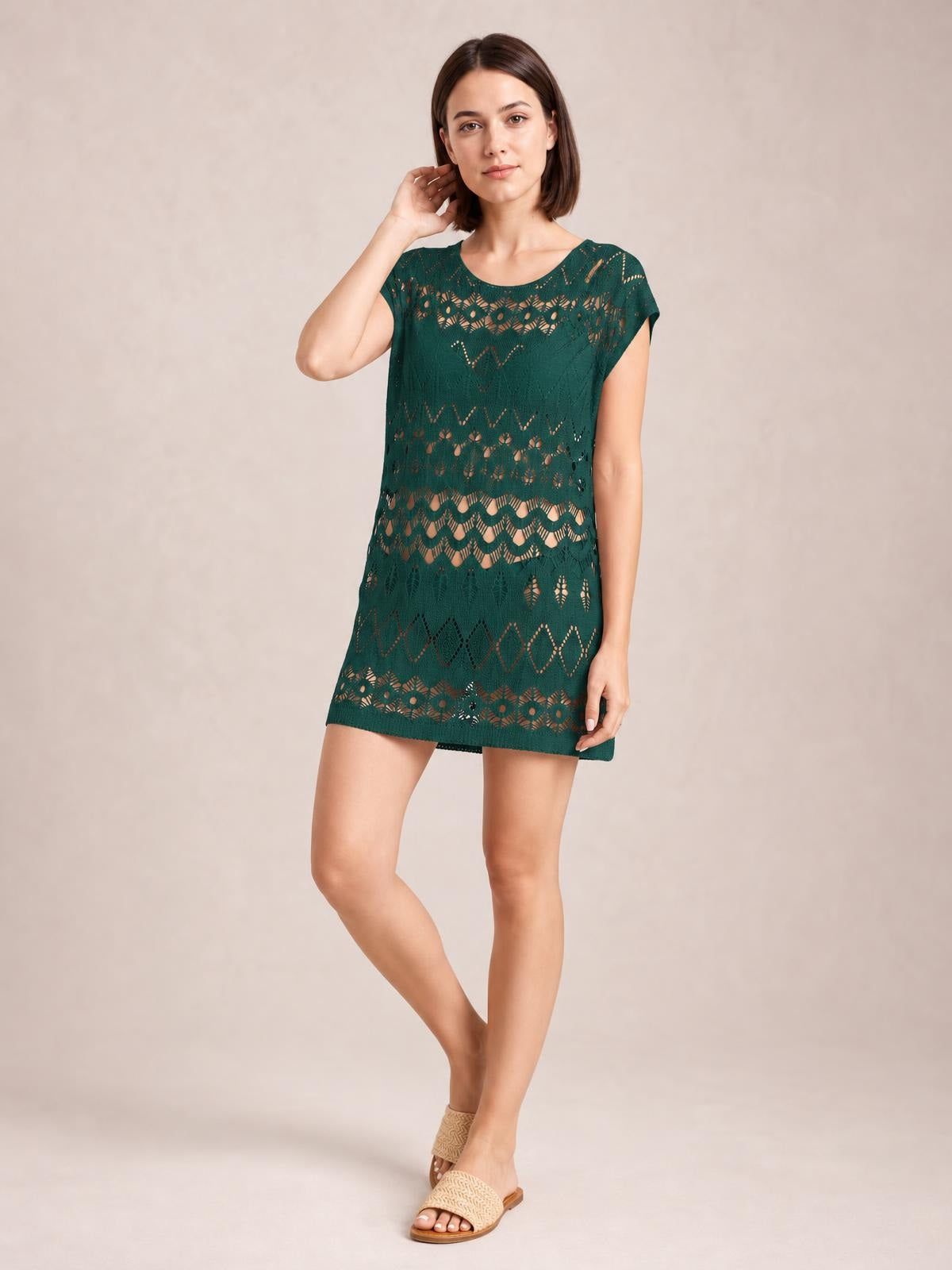 A model poses in a deep green openwork round neck cover-up with short sleeves, a relaxed straight silhouette, and an above-knee hem.