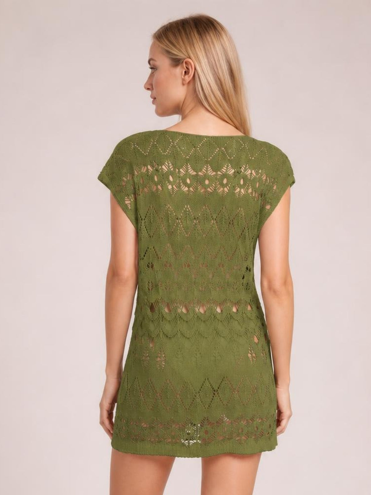 A model looks over her shoulder wearing an olive green openwork round neck cover-up with short sleeves and a relaxed, straight tunic silhouette.