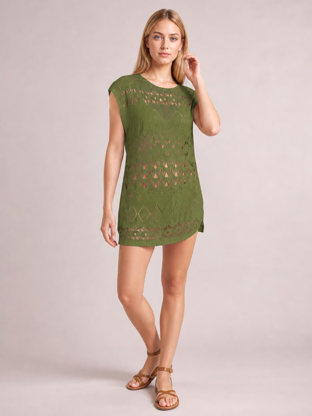 Model poses in a green openwork round-neck cover-up with short sleeves, a relaxed straight silhouette, and a curved mini-length hem.