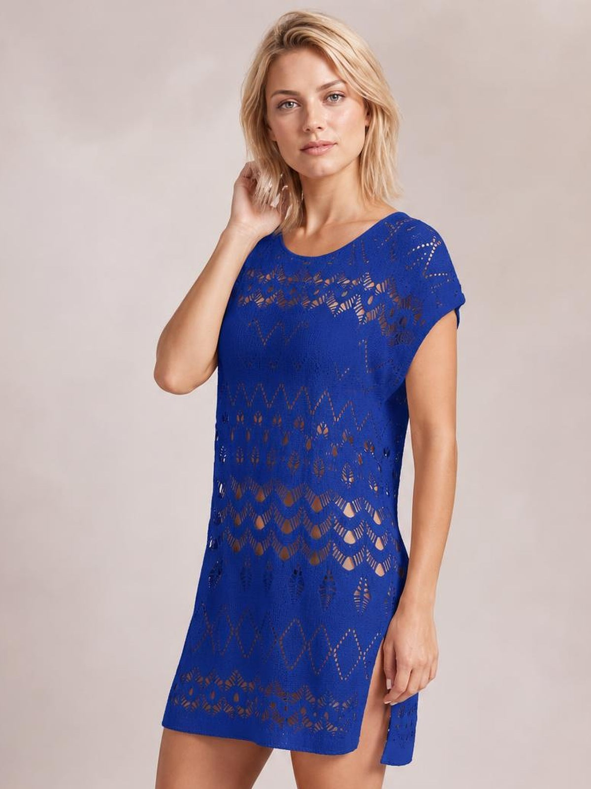 Model poses with one hand in her hair wearing a blue openwork round neck cover-up with a relaxed straight silhouette and short sleeves.