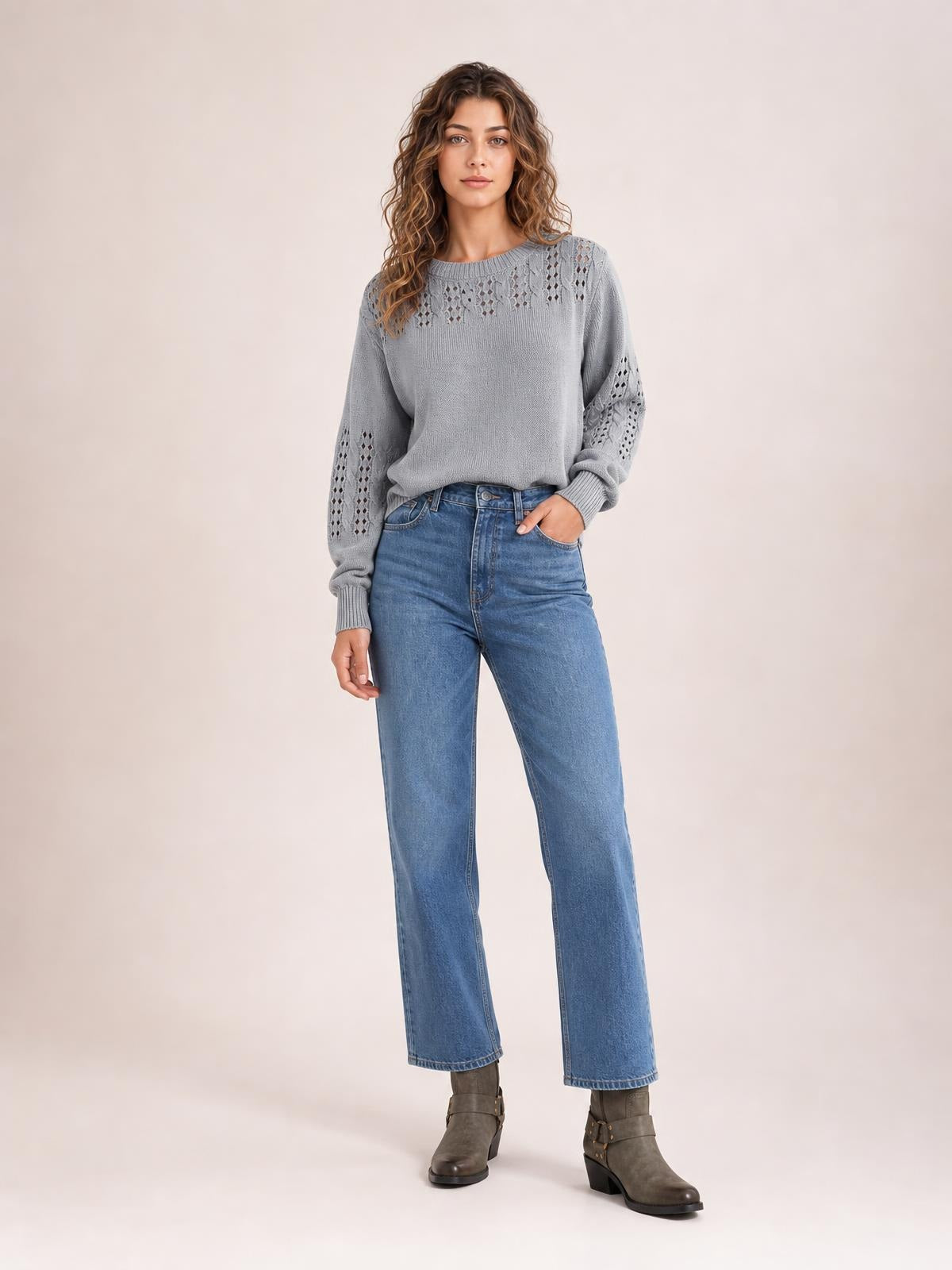 Model wearing a gray openwork round neck long sleeve sweater with a relaxed silhouette, ribbed cuffs, and patterned knit panels on the sleeves and upper chest.