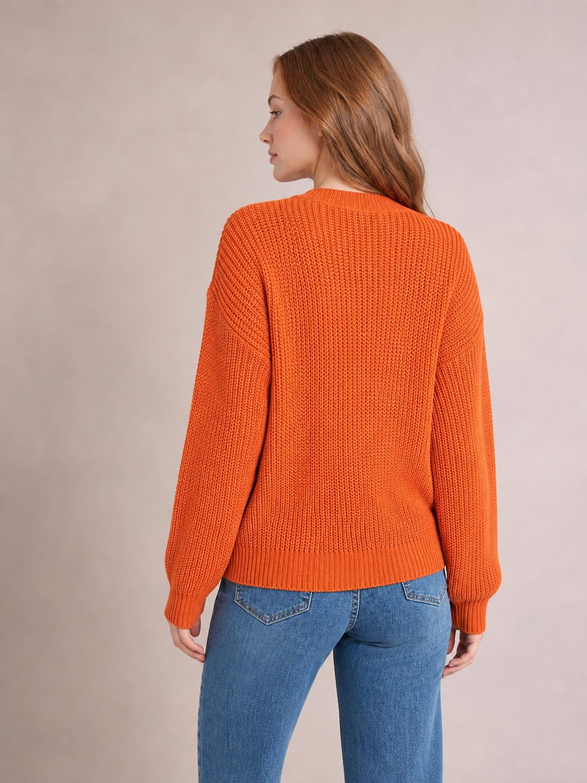 Model shown from behind wears an orange openwork round neck sweater with a relaxed silhouette, long sleeves, ribbed cuffs and hem, and blue jeans.