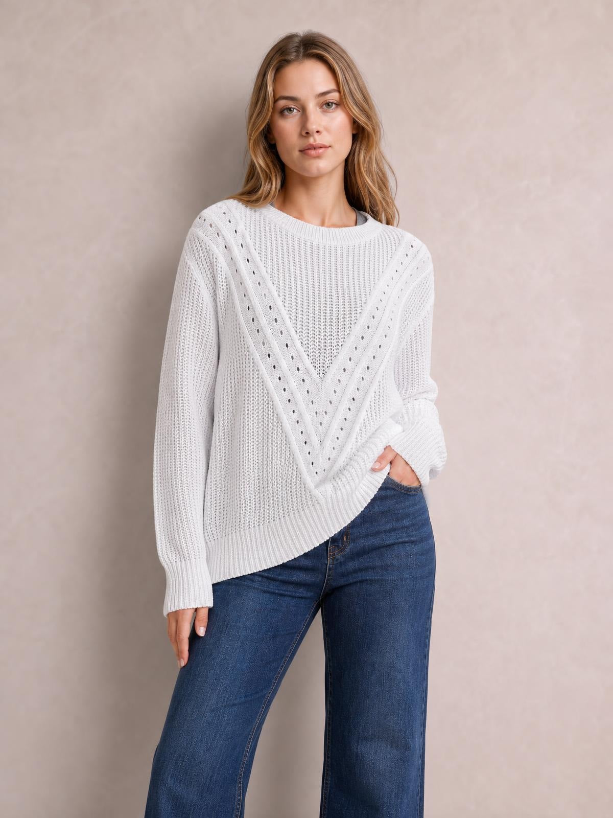 Model wears a white openwork round neck sweater with long sleeves, ribbed cuffs and hem, and a relaxed silhouette accented by a chevron knit pattern.