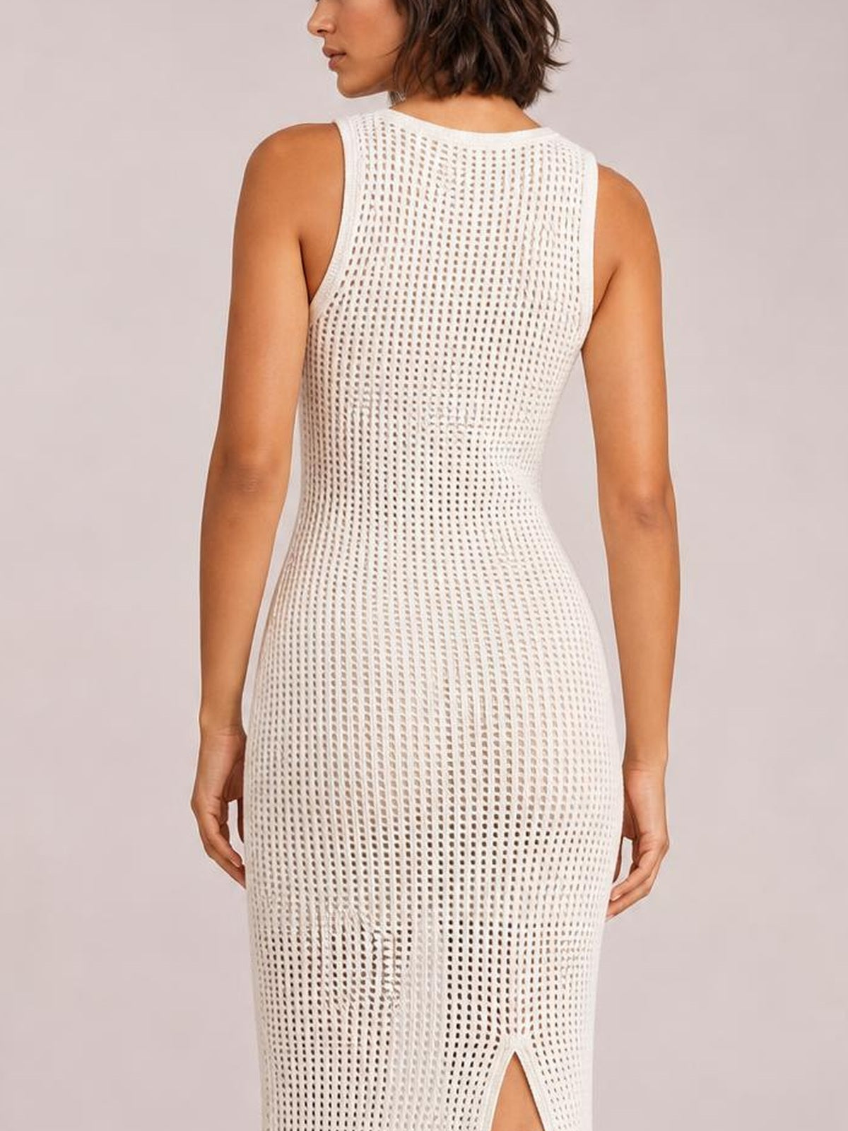 Model shown from the back wearing a white semi-sheer openwork cover-up with a round neck, fitted silhouette, and lower side slit.