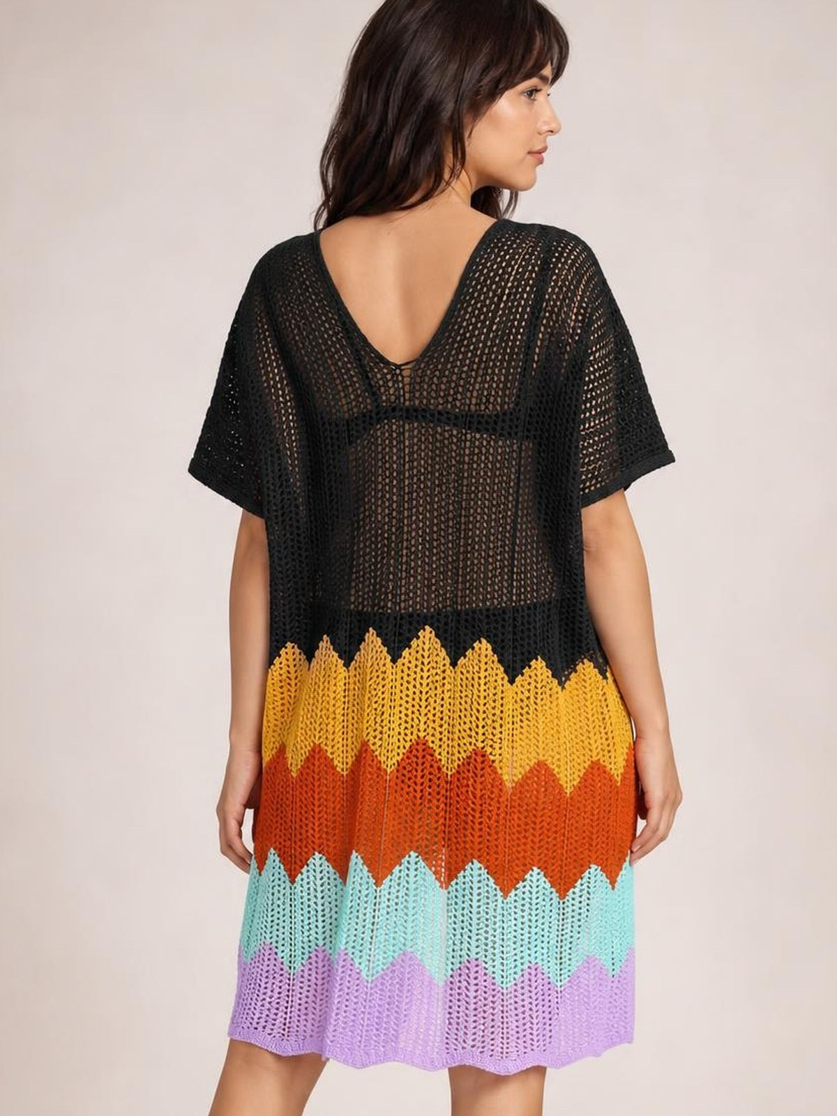 Model shown from the back wears a relaxed black openwork V-neck cover-up with half sleeves and colorful zigzag bands in yellow, orange, aqua, and lavender.