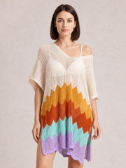 Model stands in a loose multicolor openwork V-neck half-sleeve cover-up with bold zigzag stripes, a lightweight sheer knit, and an uneven scalloped hem.