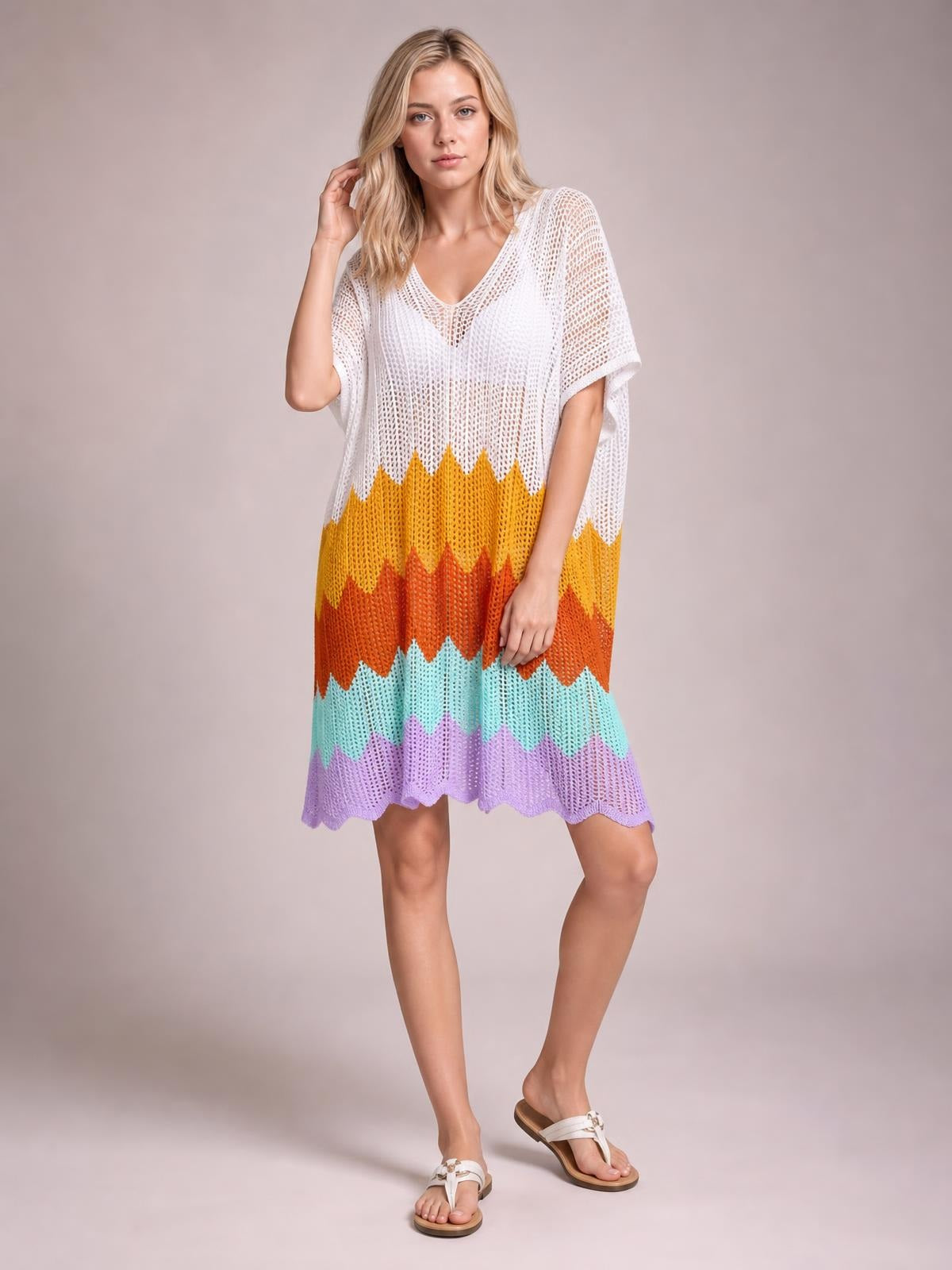 Model poses in a colorful openwork V-neck half-sleeve cover-up with a loose, flowing silhouette and scalloped hem.