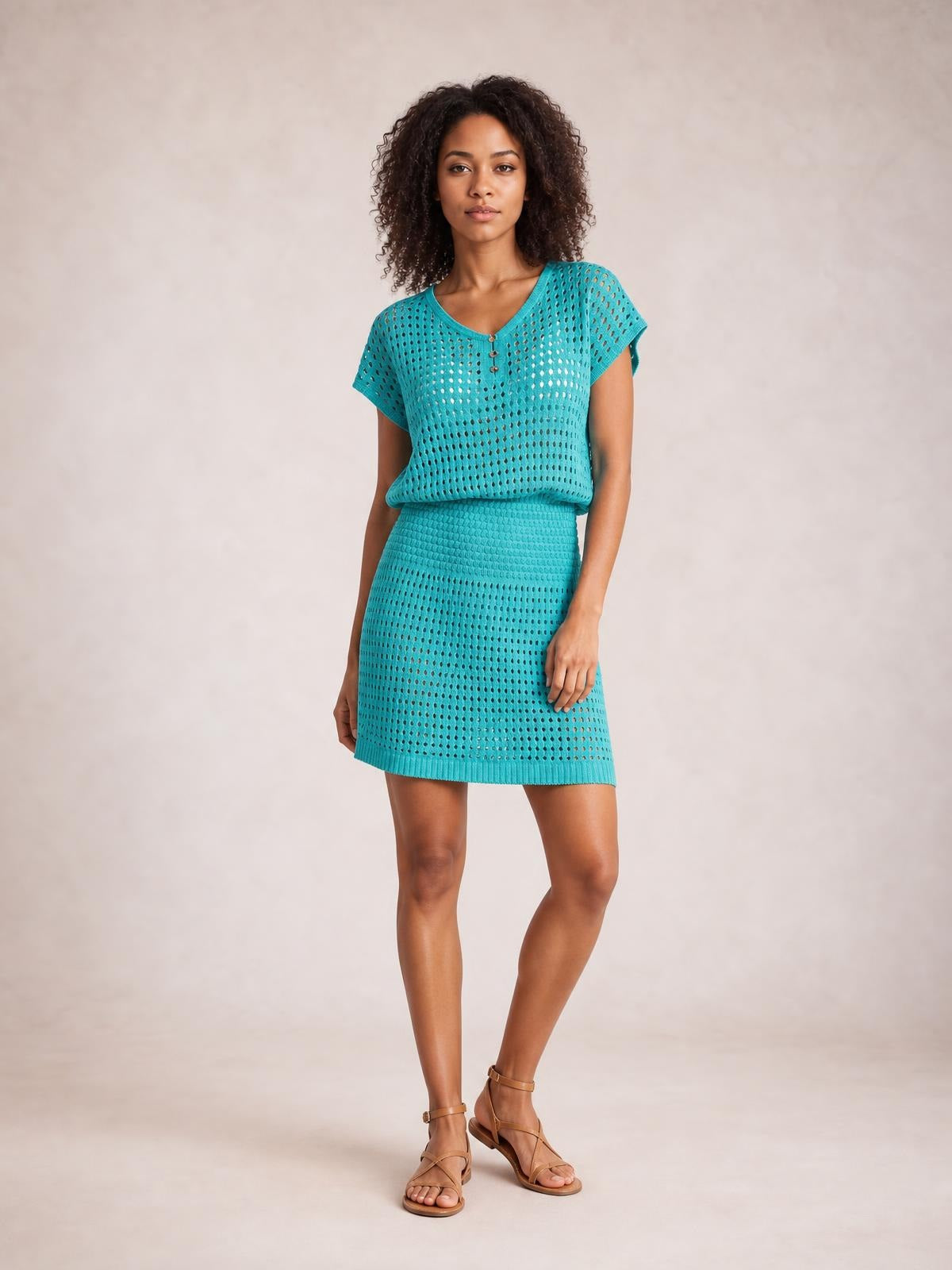 Model standing in a turquoise openwork V-neck short sleeve cover up with a relaxed silhouette, semi-sheer knit texture, and subtle front buttons.