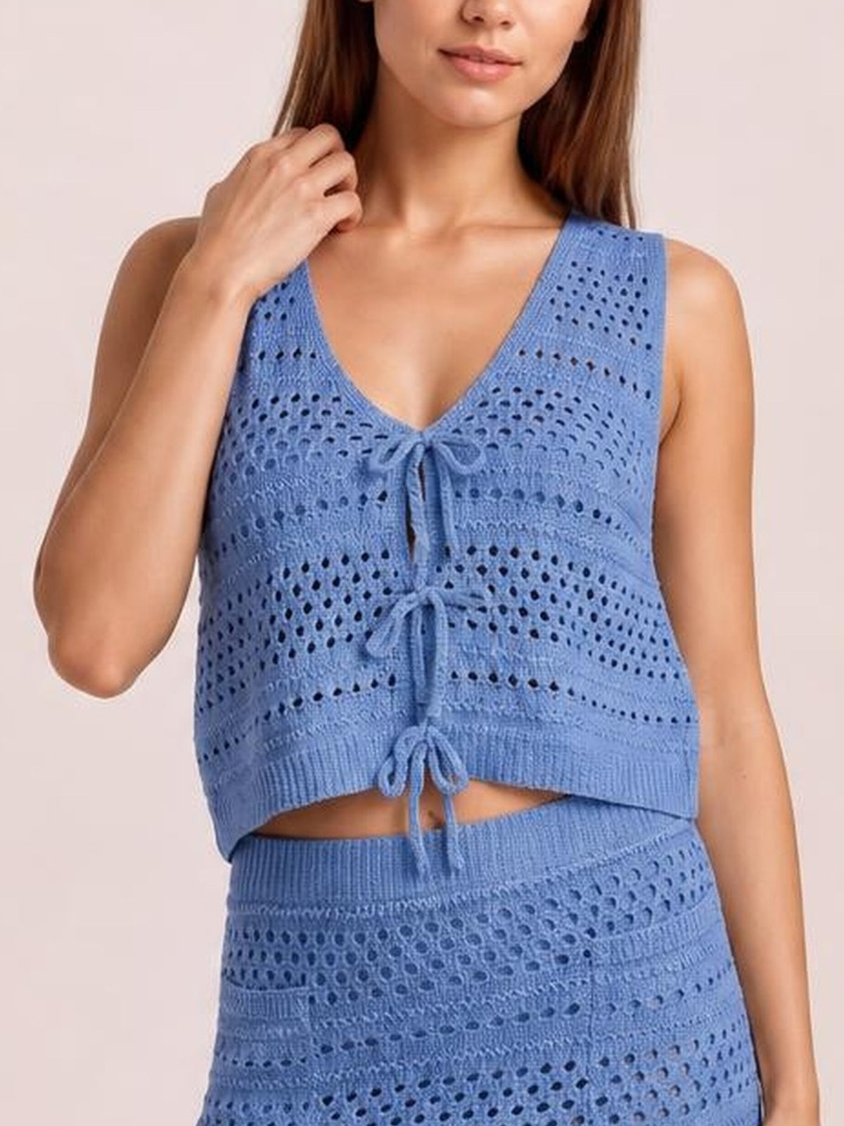 Model wearing a blue openwork knit cover-up set with a V-neck tie-front top and coordinating high-waisted skirt in a relaxed silhouette.