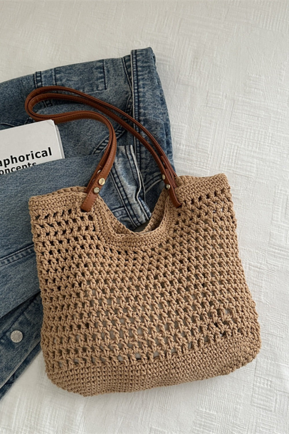 A medium tan openwork woven tote bag features a softly structured rectangular silhouette, breathable textured construction, and long brown shoulder straps.