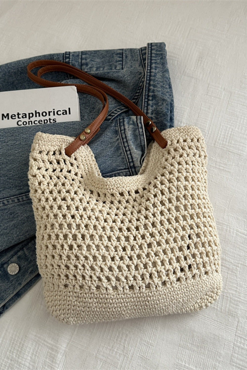 Cream openwork woven tote bag with a softly structured silhouette, textured cotton construction, and long brown shoulder straps.