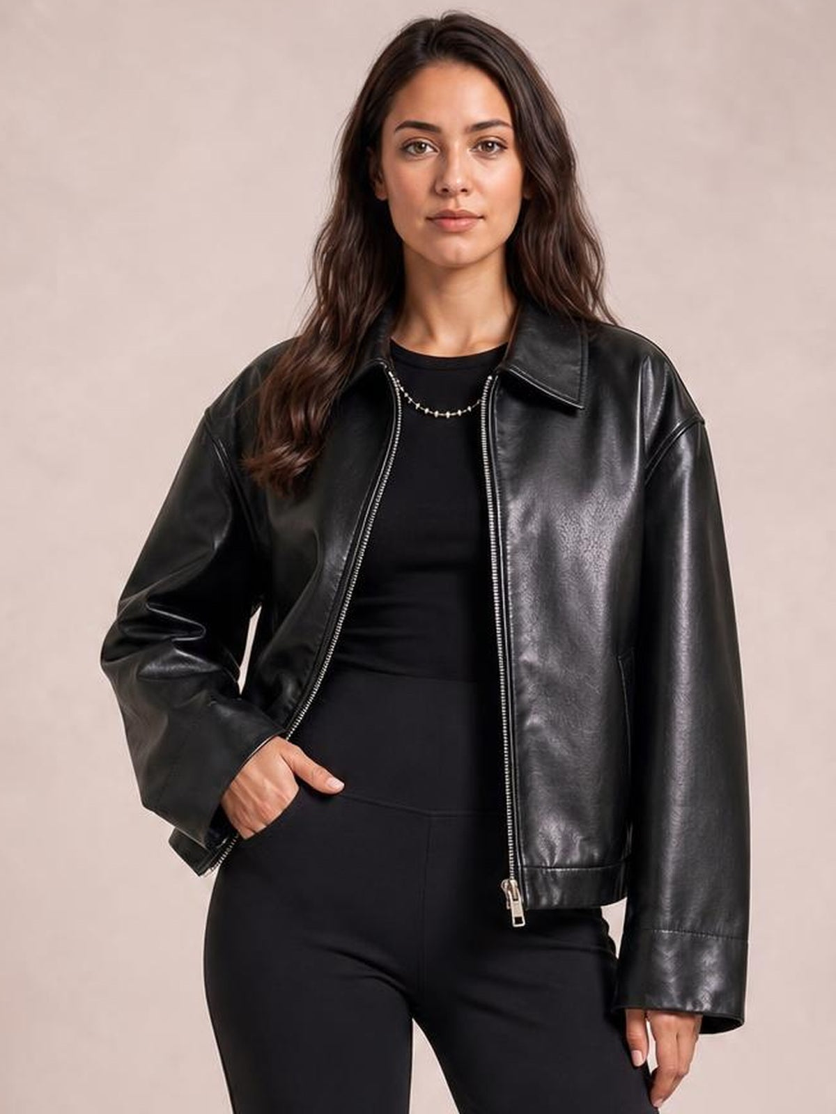 Model wearing an oversized black faux leather moto jacket with a front zip, wide collar, long sleeves, and relaxed silhouette.