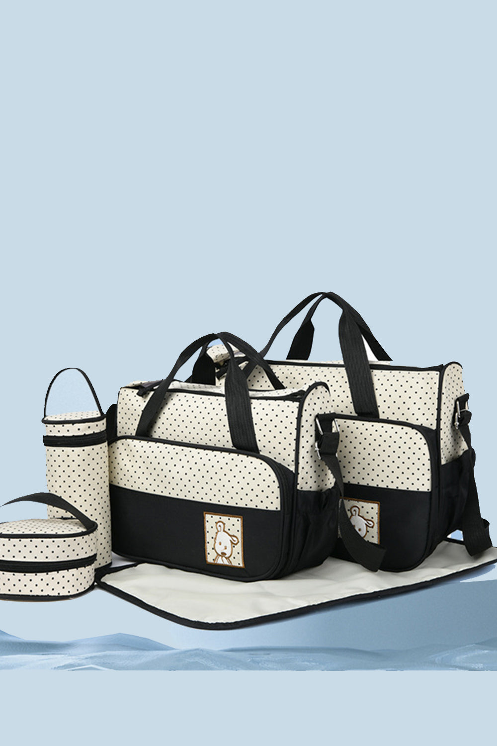 A four-piece Oxford cloth bag set features cream and black contrast totes, a bottle bag, meal bag, and matching diaper pad with structured silhouettes.
