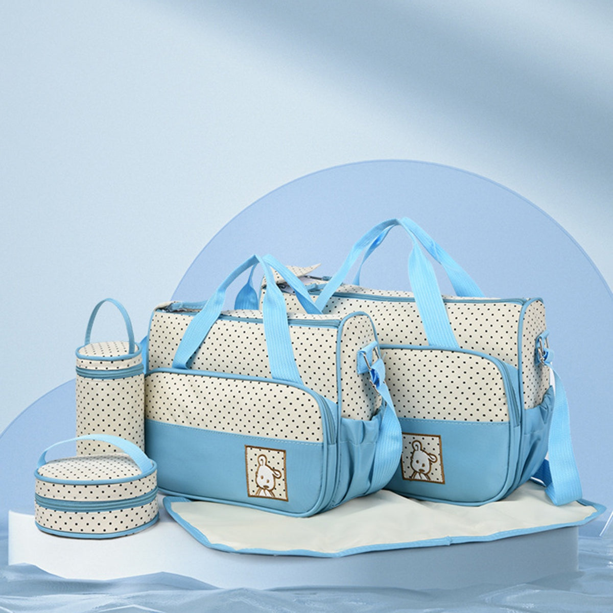 Coordinated blue and cream Oxford cloth 4-piece bag set with dotted contrast panels, structured tote handles, shoulder straps, bottle bag, meal bag, and diaper pad.
