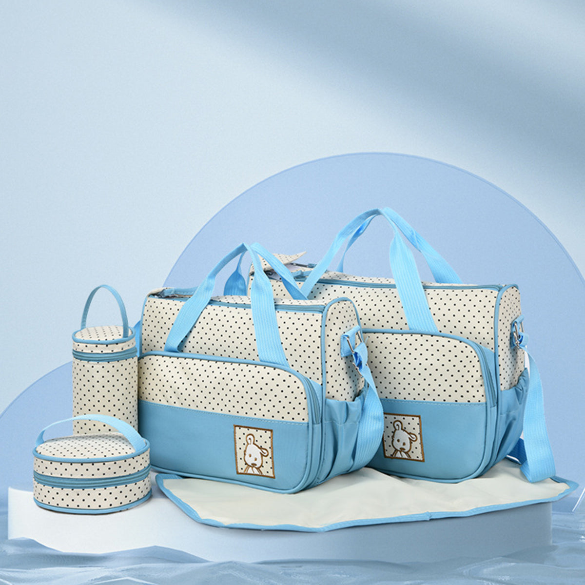 Coordinated blue and cream Oxford cloth 4-piece bag set with dotted contrast panels, structured tote handles, shoulder straps, bottle bag, meal bag, and diaper pad.