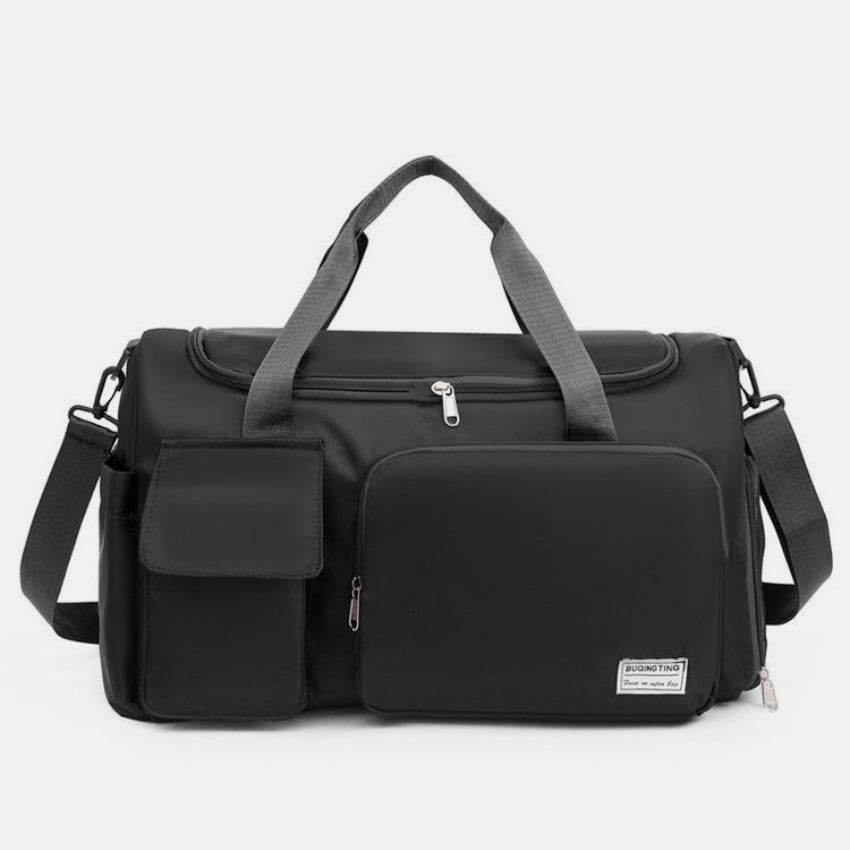 Oversize black oxford cloth travel bag with a structured silhouette, dual top handles, detachable shoulder strap, zippered main compartment, and front pockets.