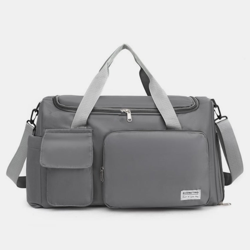 Oversize gray oxford cloth travel bag with a structured silhouette, dual top handles, detachable shoulder strap, zippered main compartment, and front flap pockets.