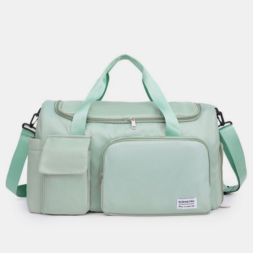 Mint green oversize oxford cloth travel bag with a structured silhouette, dual top handles, detachable shoulder strap, and multiple zippered and flap-front pockets.